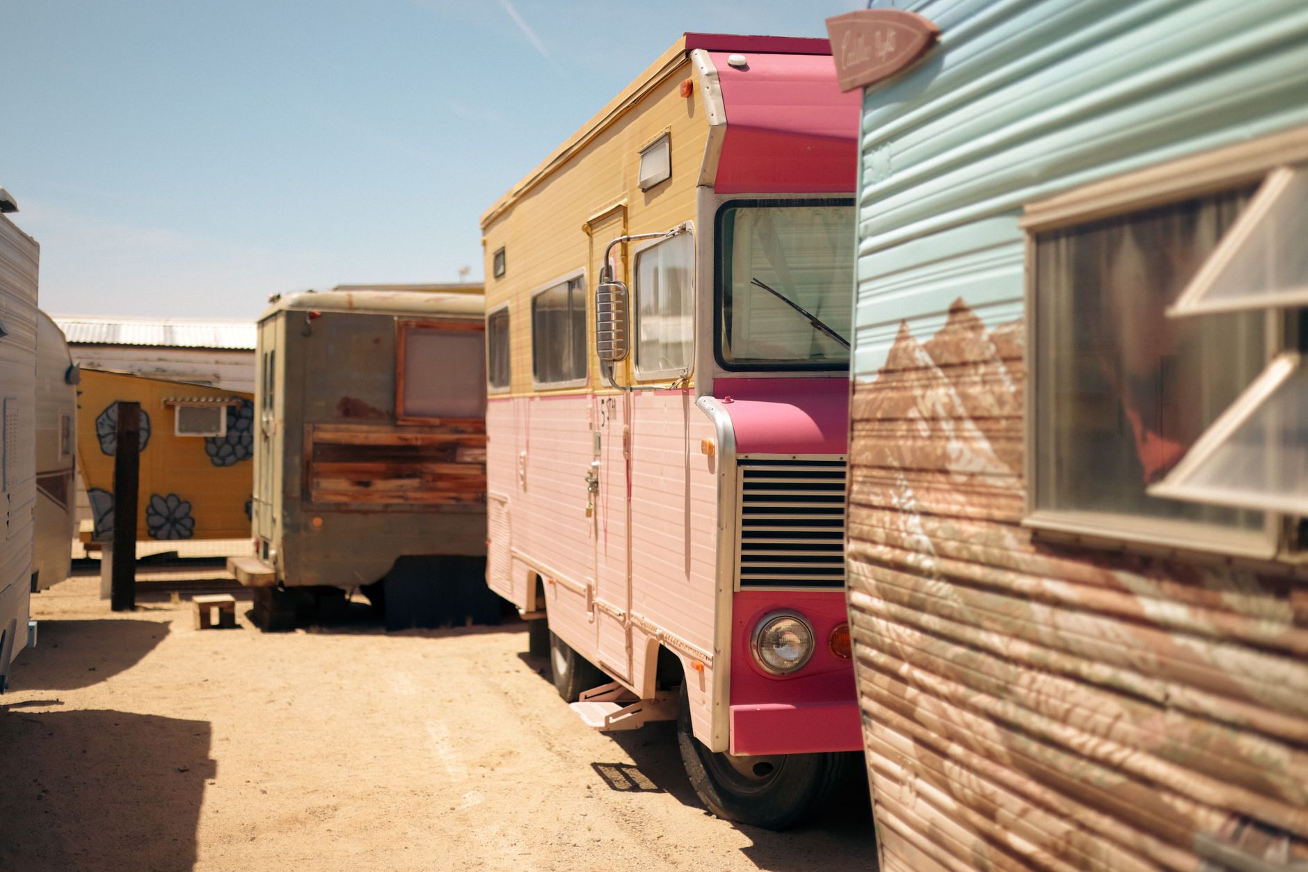 Colorful vintage campers and RVs parked in desert lot, showcasing recreational vehicles requiring California registration