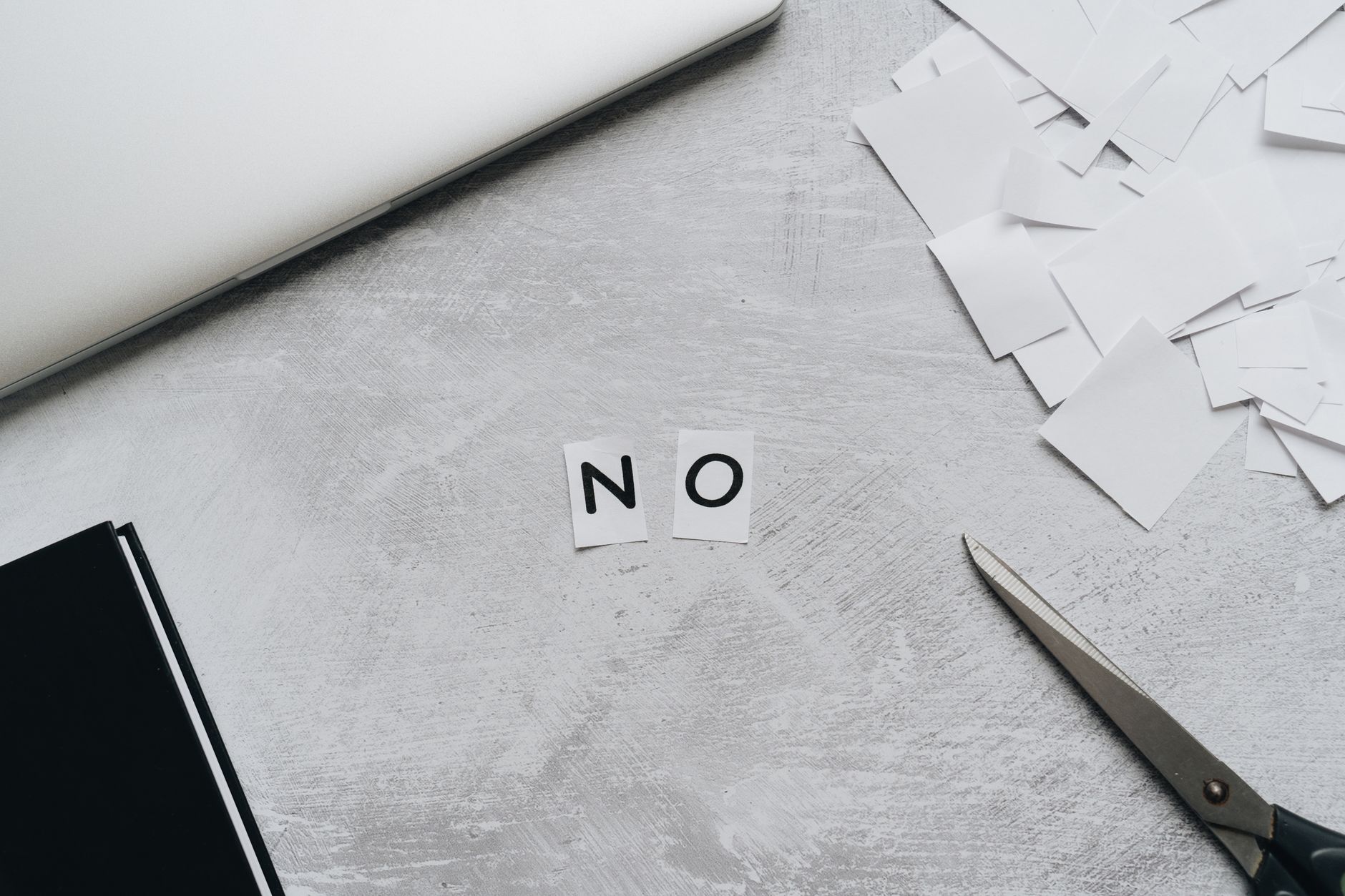 White tiles spelling NO on wooden desk with scissors and paperwork, representing registration denial reasons.