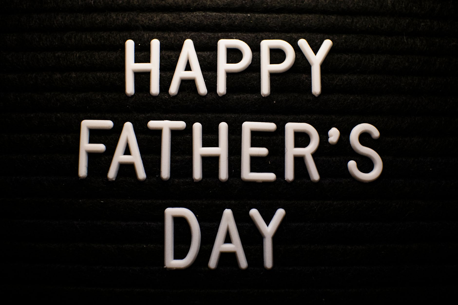 Happy Father's Day text in white letters on dark brick background for holiday greeting
