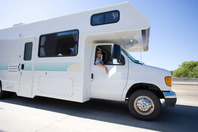 Modified RV with rooftop solar panels and custom exterior upgrades parked along an open highway.