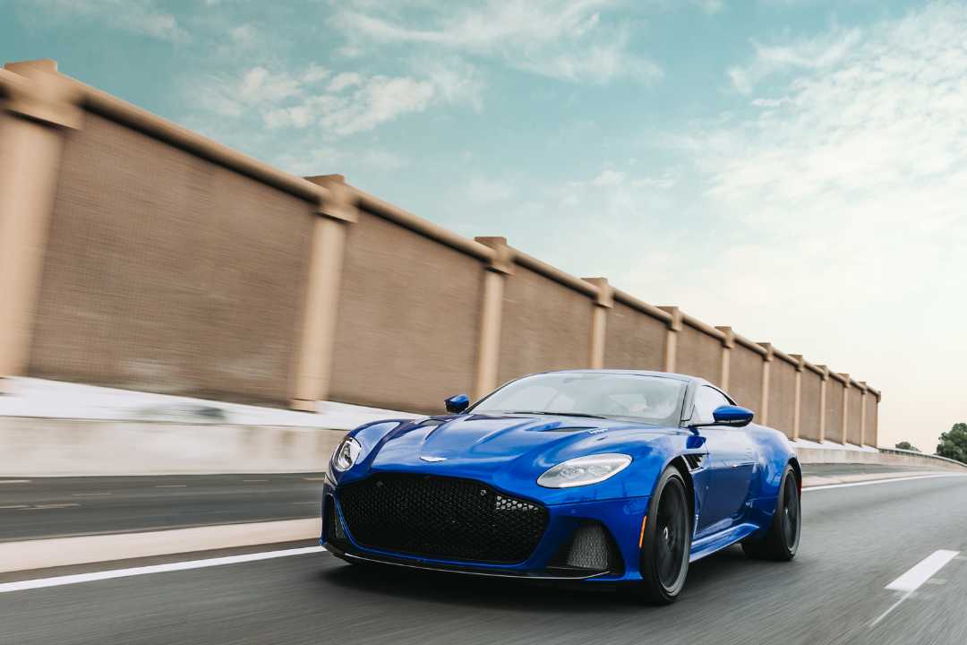 Blue coupe driving on open road under clear sky, representing vehicle ownership updates and how to fix a written mistake on a car title when selling. Blue coupe driving on open road under clear sky, representing vehicle ownership updates and how to fix a written mistake on a car title when selling.