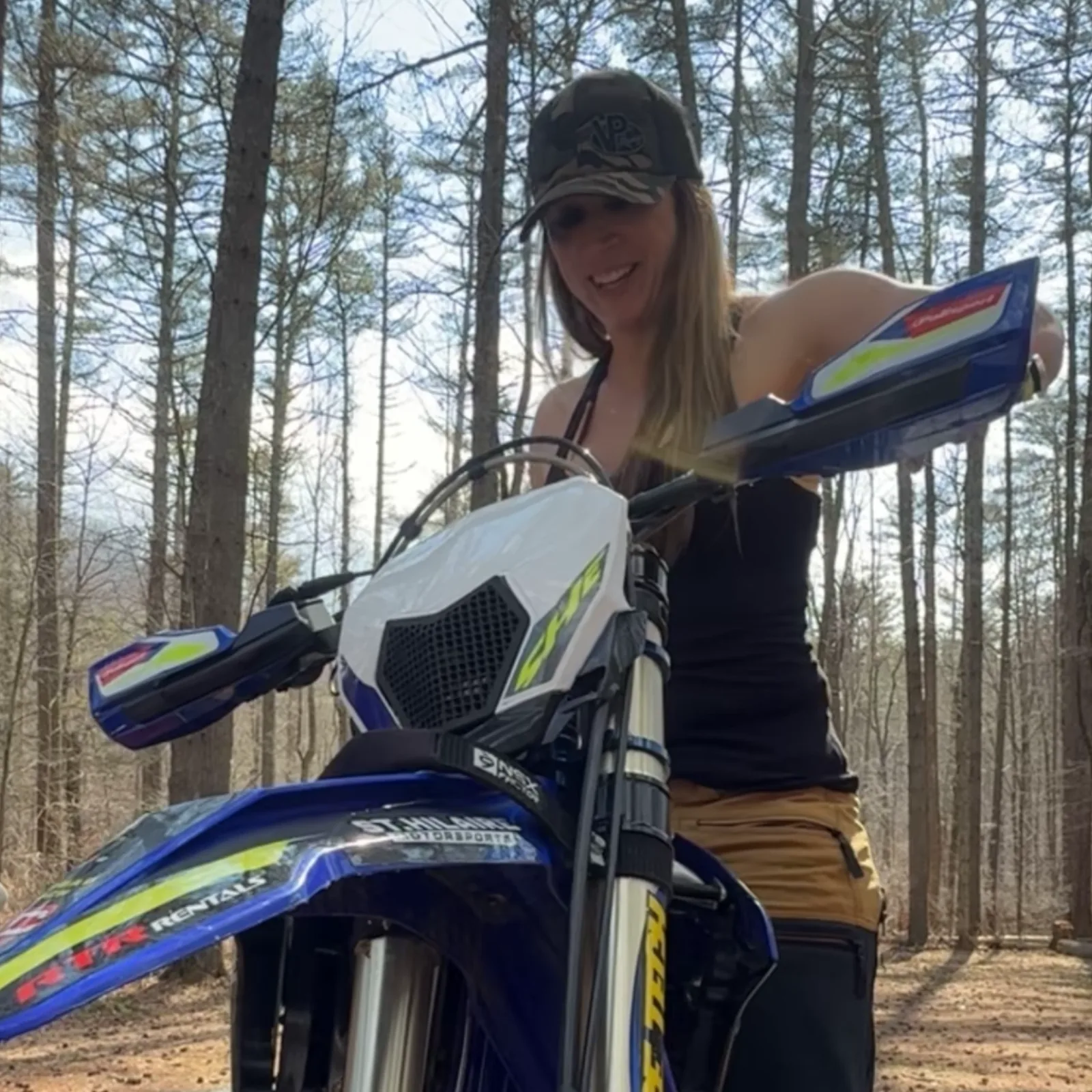 Crystalmarie adjusting the handlebars on her dirt bike in the woods