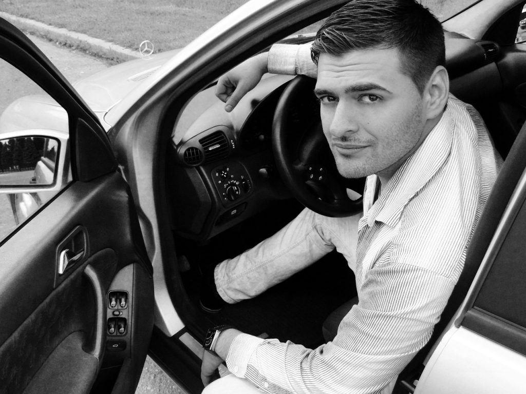 Man sitting in driver's seat of Mercedes car, holding steering wheel