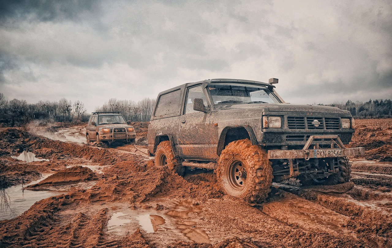 Muddy trucks off-roading through challenging terrain and water obstacles