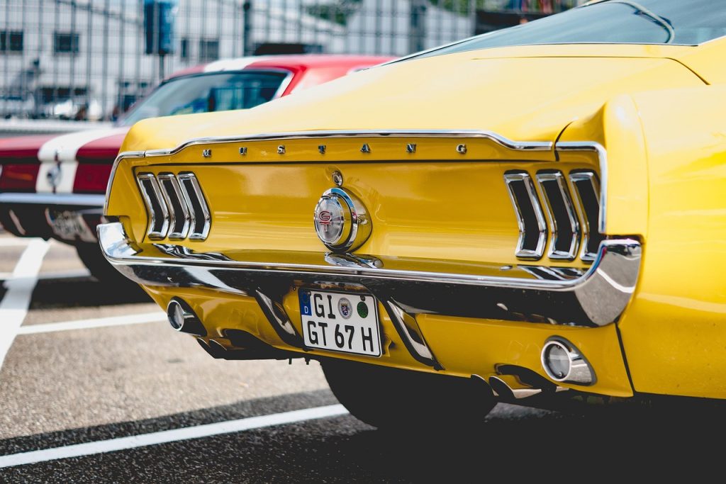Vintage yellow Mustang with chrome details parked at car show