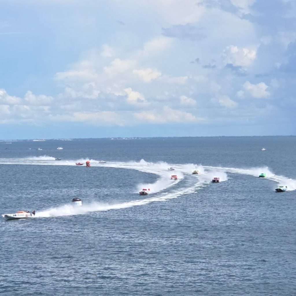 Multiple speedboats racing across ocean waves with white spray