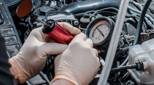 Mechanic checking red car engine coolant reservoir level