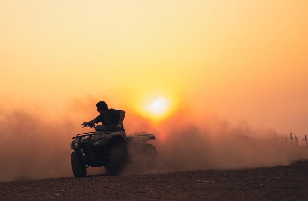 Rider on ATV kicking up dust at sunset, illustrating recreational off-road vehicle use requiring Montana registration