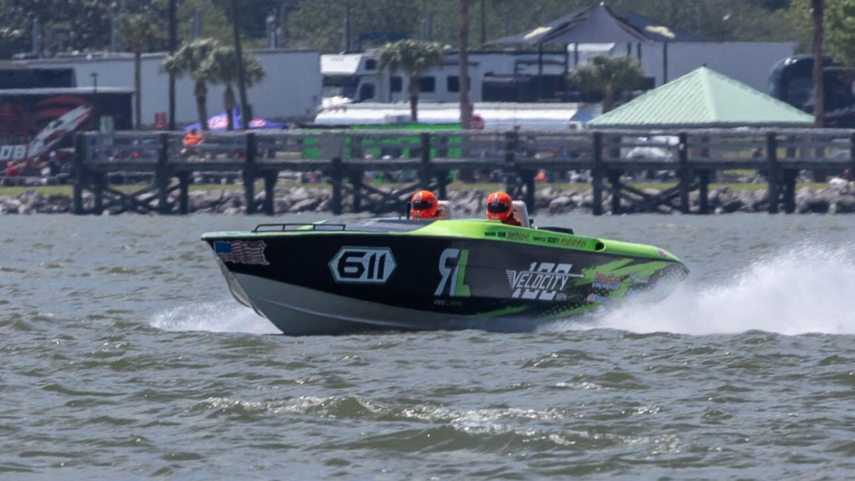 Ride Legal Velocity powerboat #611 charging through choppy water head-on, with both crew members in orange helmets visible, competing at Thunder on Cocoa Beach