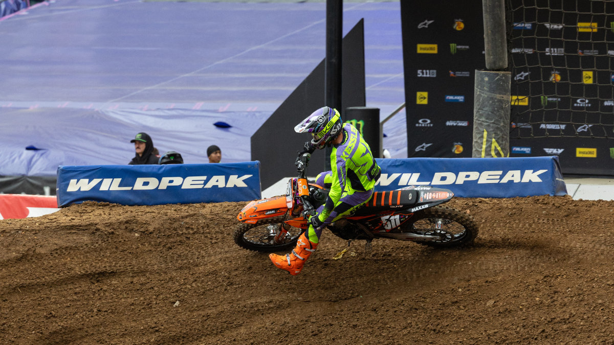 A professional motocross rider on a Dirt Legal race bike rails a deep, rutted dirt turn during a hard-fought motocross race.