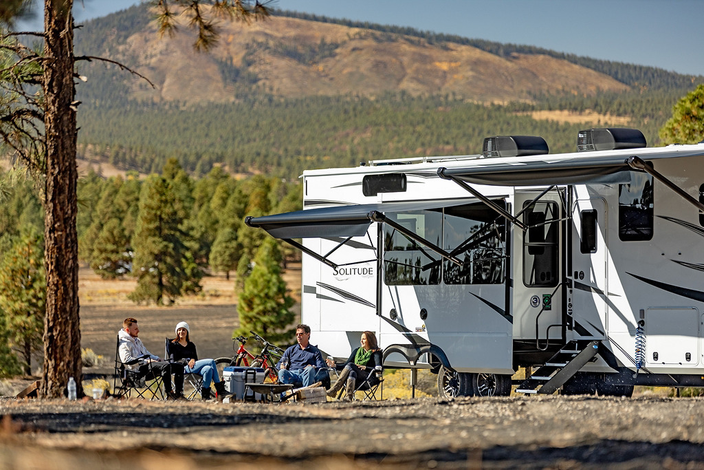 Family enjoying RV camping trip with travel trailer in scenic mountain forest setting