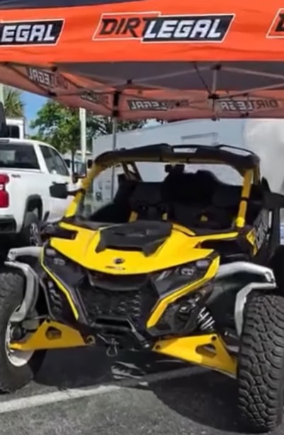 Yellow and black street legal UTV on display under tent at dealership showing Florida-compliant off-road vehicle