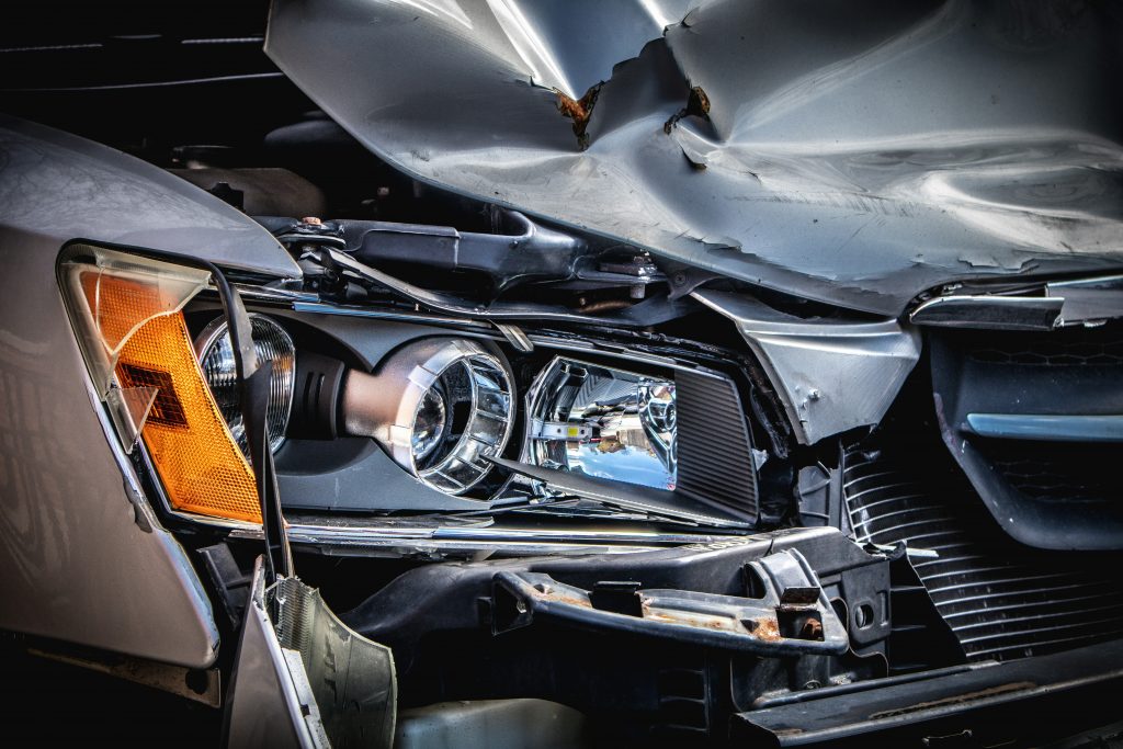 Severely damaged vehicle front end from collision, illustrating importance of defensive driving and accident prevention