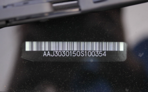 Close-up of vehicle VIN barcode label showing identification number for authenticity verification and fraud detection checks.