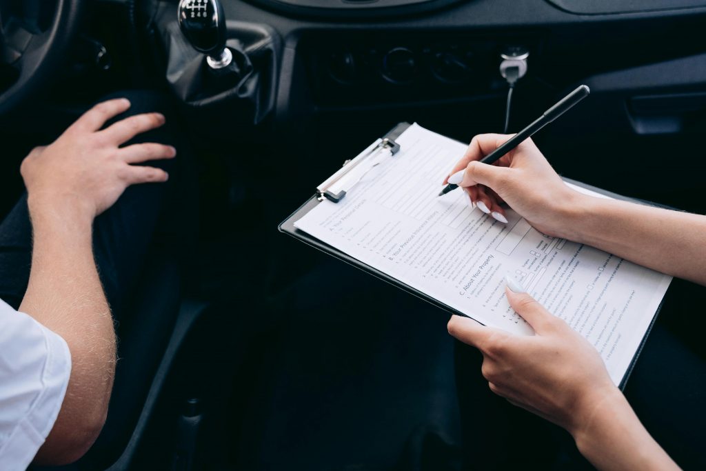Insurance agent inspecting vehicle with clipboard, documenting Montana LLC registration and title compliance paperwork