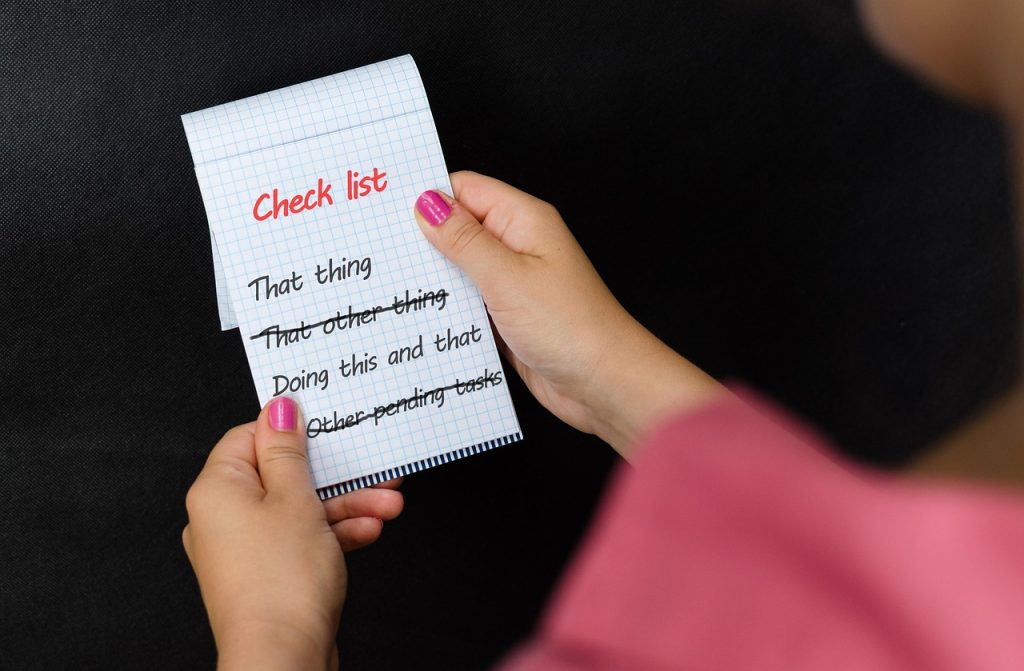 Woman holding checklist with tasks including car selling reminders and pending items to complete