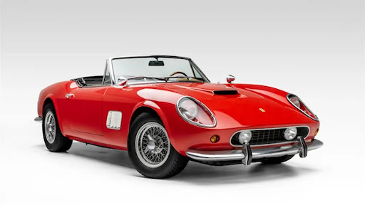 A bright red classic Ferrari convertible with sleek curves, chrome bumpers, and wire-spoke wheels is displayed against a clean white background, showcasing its timeless vintage sports car design.