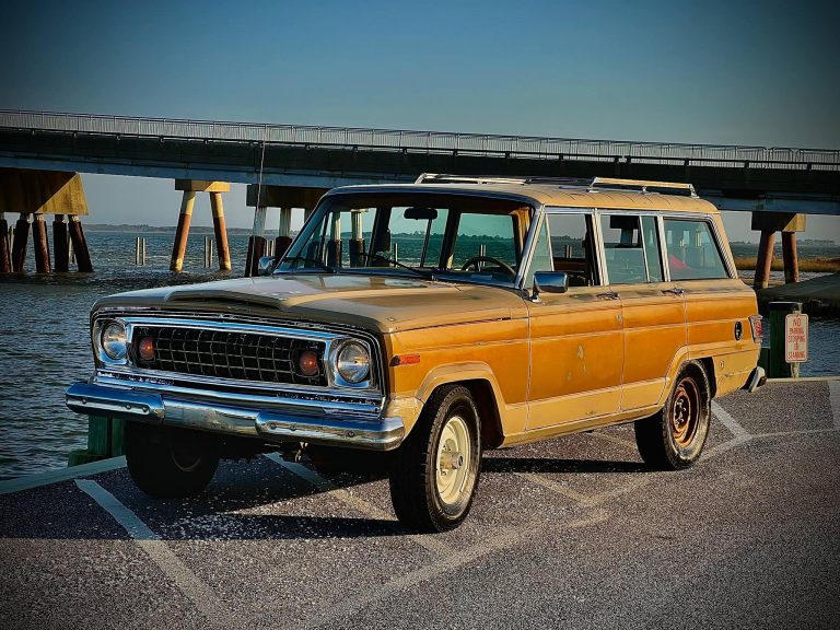 Restored orange Jeep Wagoneer parked at waterfront pier symbolizing resilience and freedom through automotive restoration