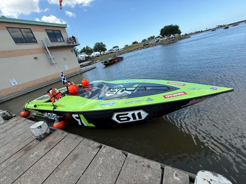 The Ride Legal Velocity VR1 race boat number 611 docked at a race event with a checkered flag on board.