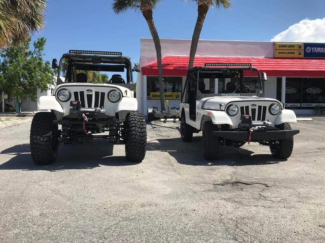 Two white modified Jeep-style Roxor vehicles parked at dealership showcasing off-road customization upgrades