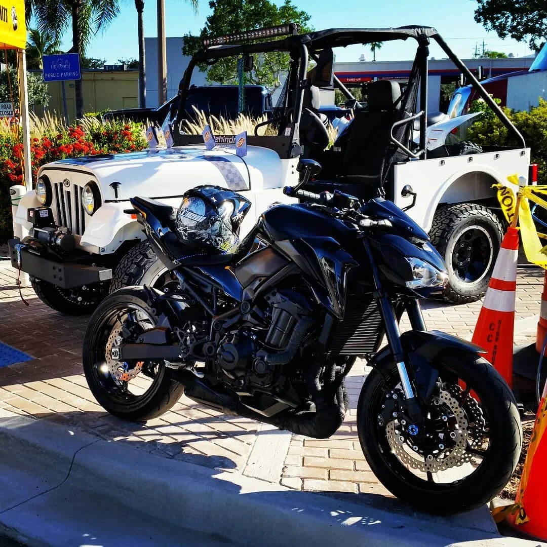 Custom motorcycle and Jeeps displayed at outdoor vehicle showcase event featuring modified off-road vehicles