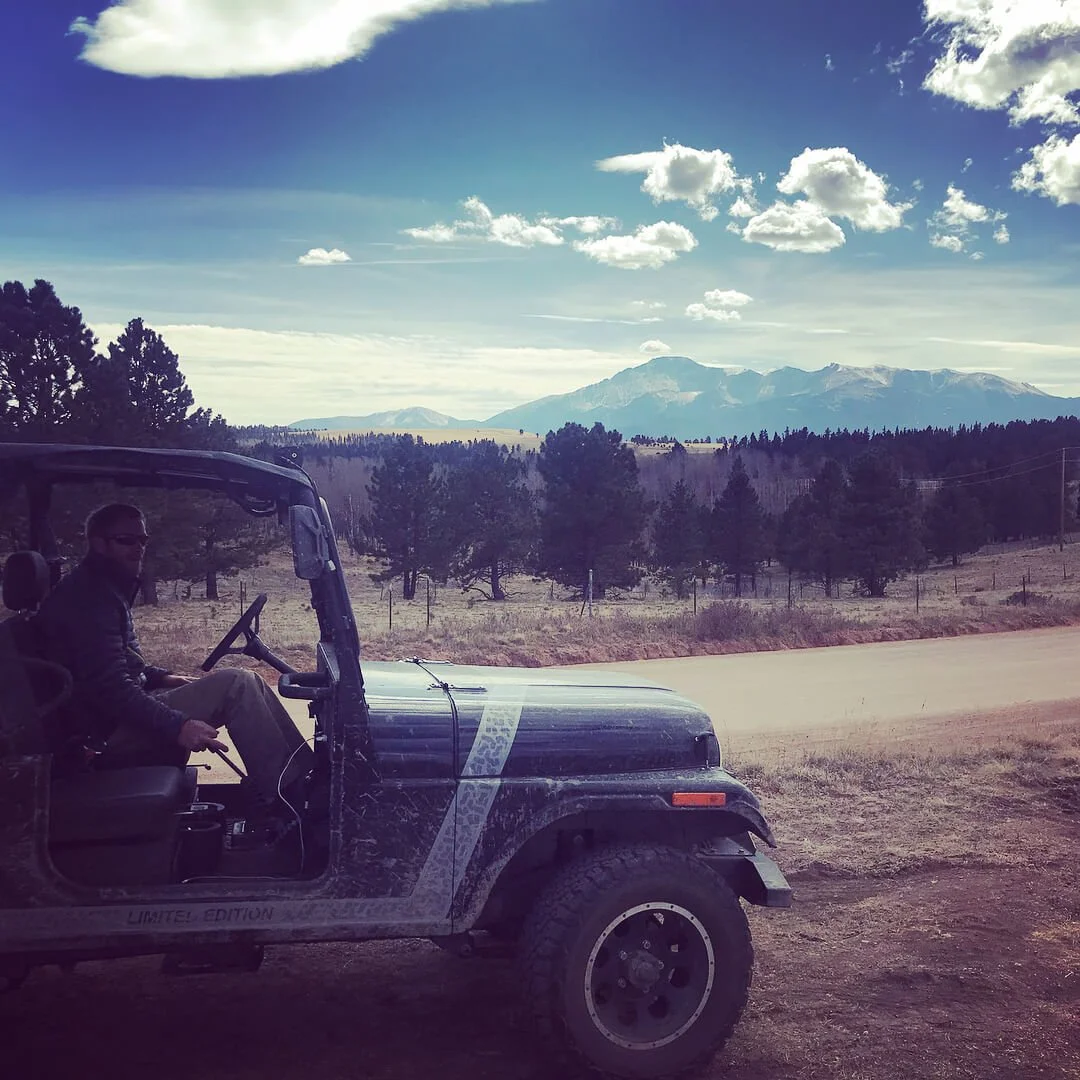 Mahindra Roxor off-road vehicle parked overlooking mountain landscape and forest terrain during adventure drive.