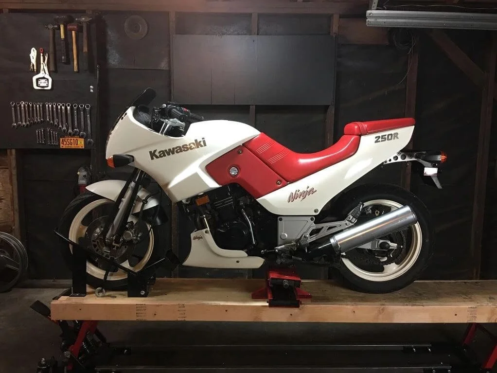 Kawasaki Ninja 250R beginner motorcycle mounted on lift in professional garage workshop for maintenance and repair training