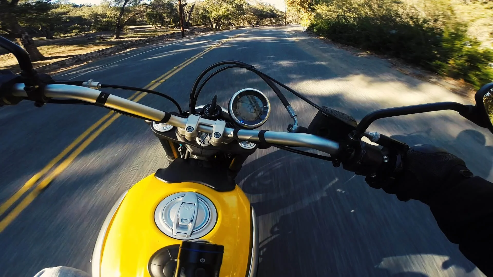 Yellow motorcycle on scenic tree-lined road, first bike riding adventure preparation