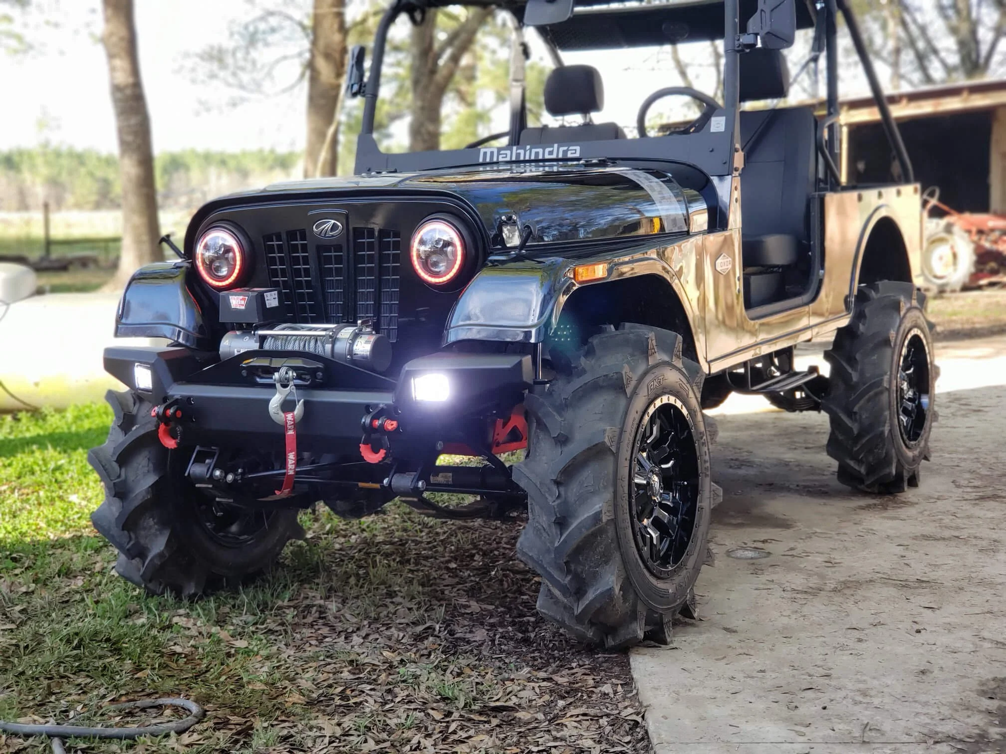 Modified black Mahindra Roxor with LED headlights and winch parked outdoors during daylight hours.