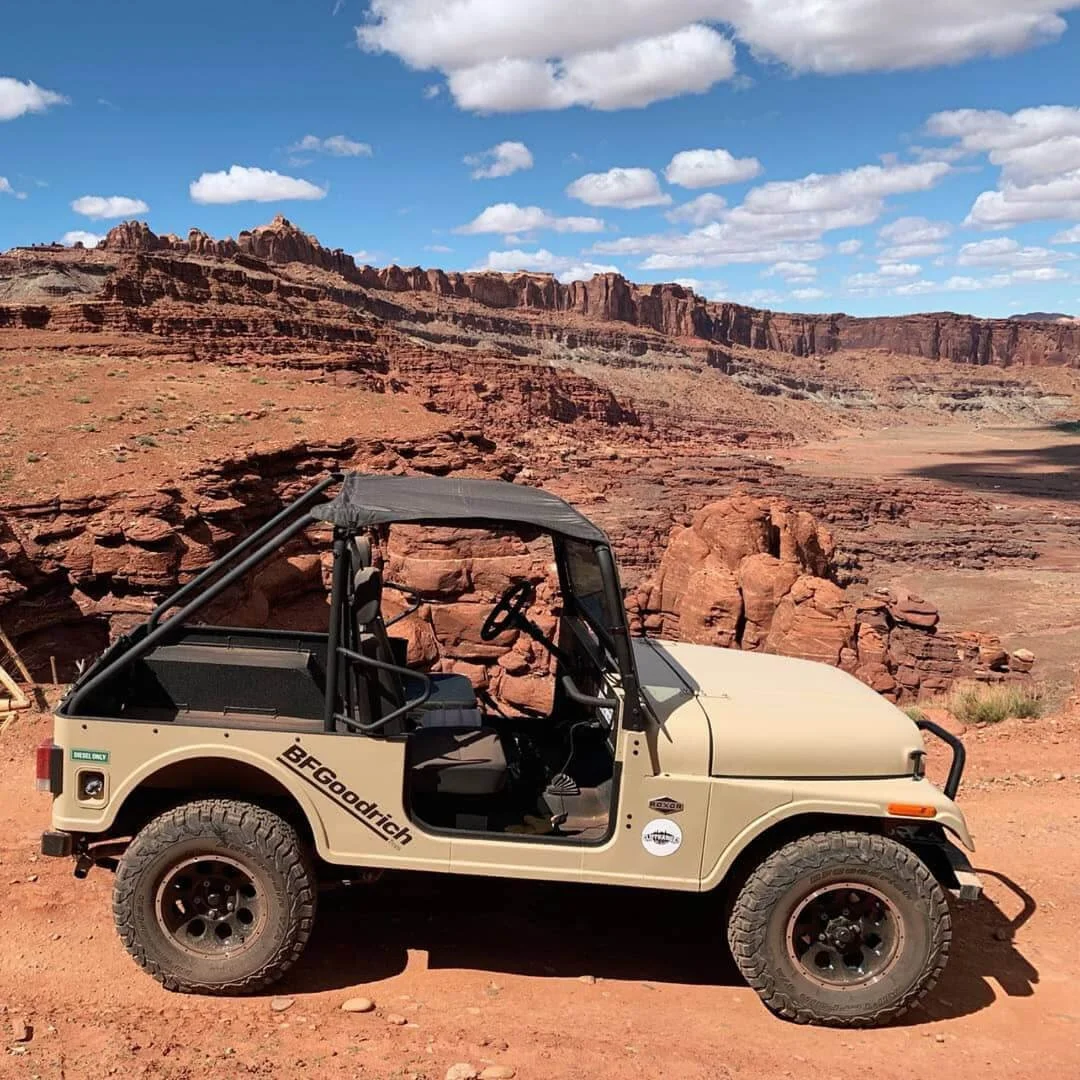 Mahindra Roxor beige open-air vehicle parked in red rock desert landscape with canyon formations