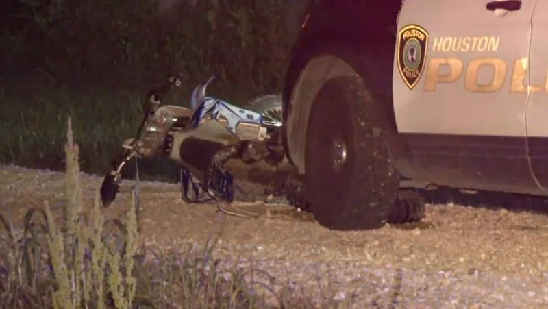 Dirt bike parked next to Houston police vehicle on dirt road during nighttime traffic stop pursuit