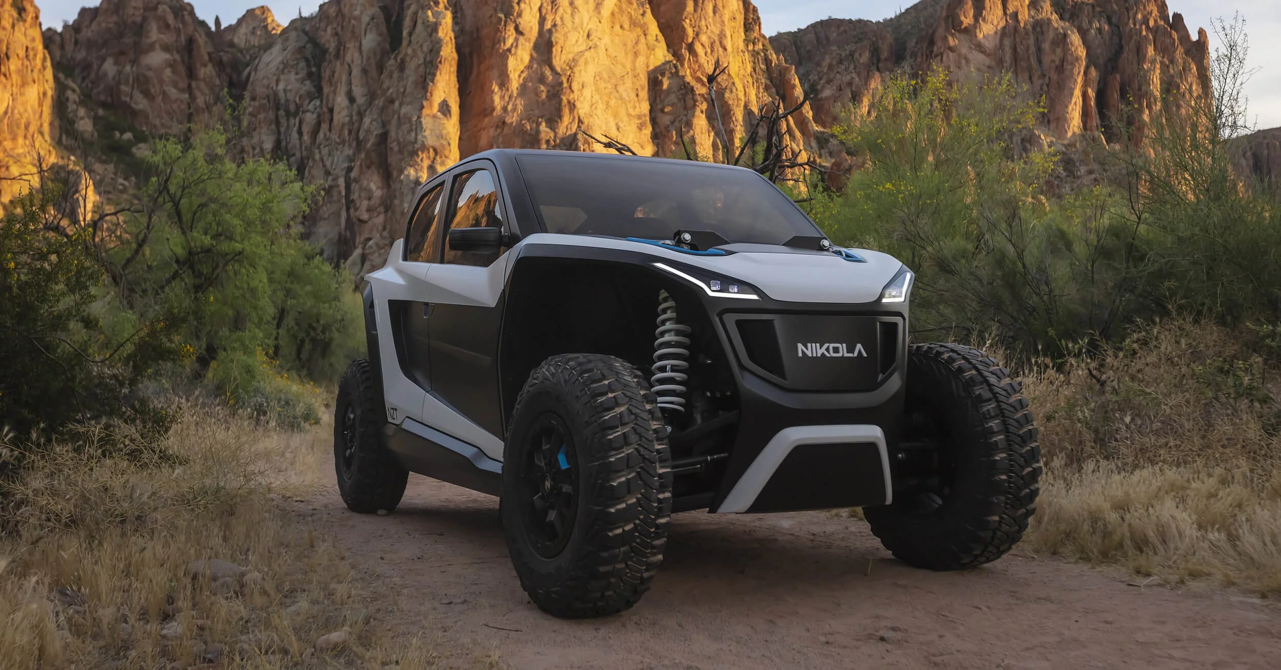 Nikola NZT electric UTV parked on desert trail with dramatic rocky canyon cliffs in background