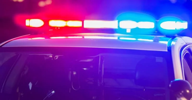 Police vehicle with flashing red and blue emergency lights at night, illustrating law enforcement response to crime.