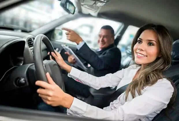 Woman sitting in driver's seat of car during dealership visit