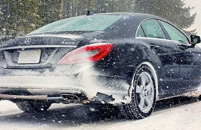 Black Mercedes sedan covered in snow during winter, demonstrating proper vehicle winterization and cold weather preparation