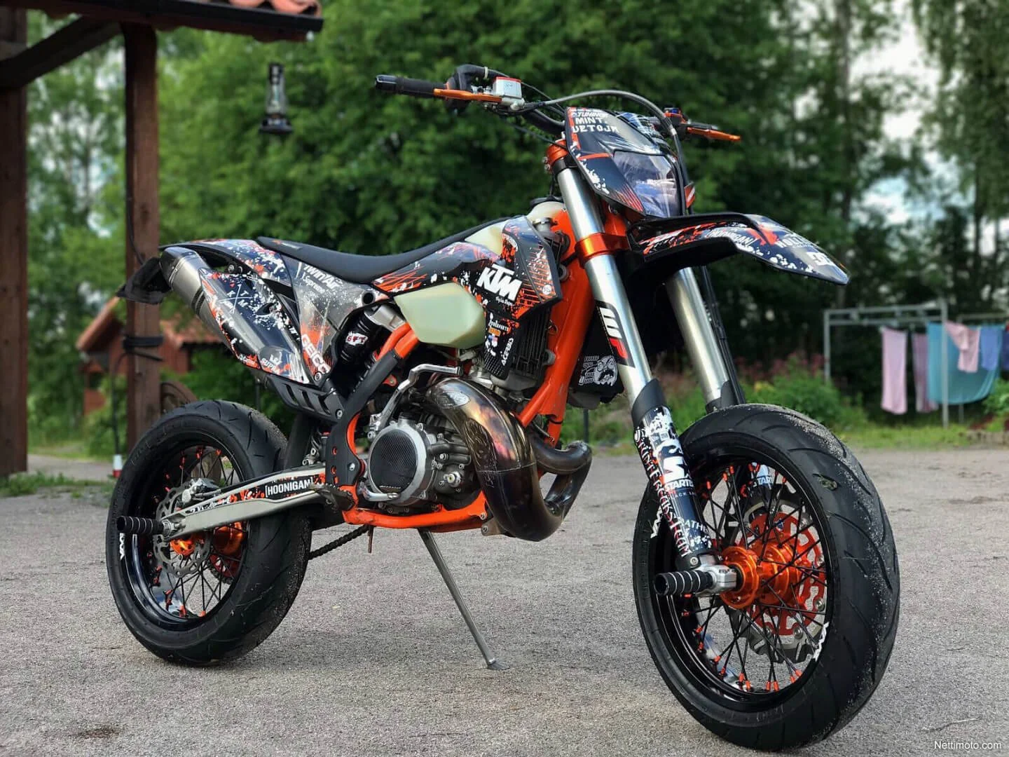 Custom KTM dirt bike with orange frame and Hoonigan graphics parked outdoors, showcasing titled street legal dirt bike.