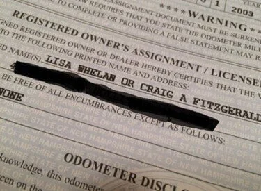 Damaged car title document showing torn, stained, and marked paper with redacted owner information and odometer disclosure