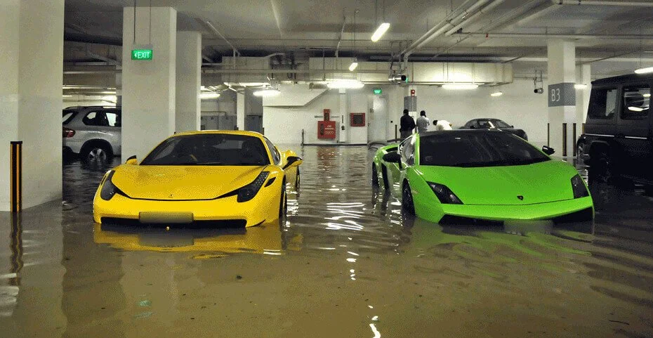 Elevated sports cars flooded in parking garage, illustrating risks of title-washed vehicles from flood damage and hidden