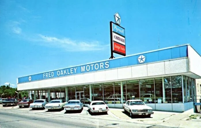 Vintage Fred Oakley Motors dealership storefront with classic cars parked outside