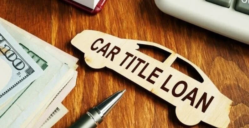 Car title loan wooden cutout with cash and pen on desk representing vehicle financing options