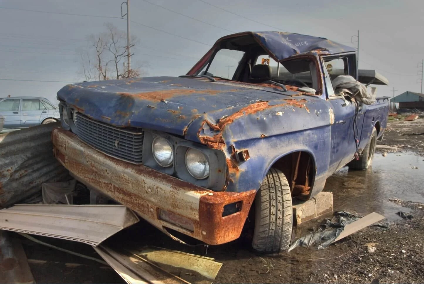 Heavily rusted blue pickup truck with damaged cab in junkyard illustrating junk title and salvage vehicle concepts