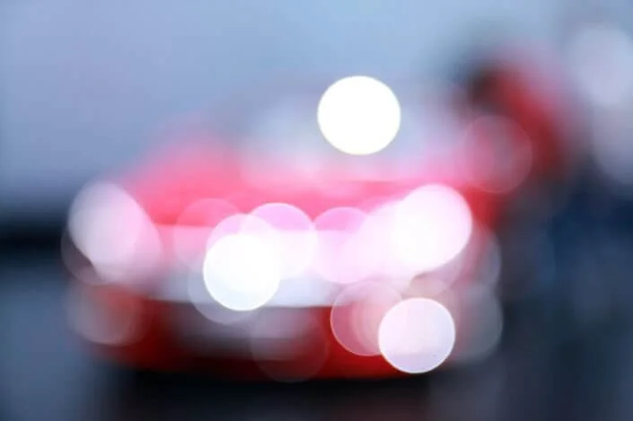 Blurred red car with bokeh lights at night, illustrating vehicle surety bond concepts and auto insurance requirements.