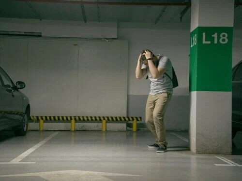 Woman photographing empty parking garage spot after stolen car, documenting vehicle theft for insurance claim