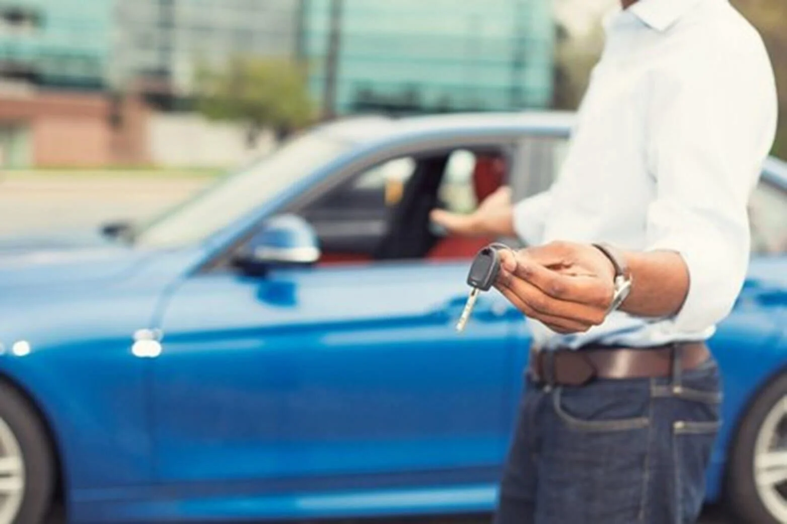Man holding car keys in front of blue vehicle, demonstrating car sale and liability transfer documentation process