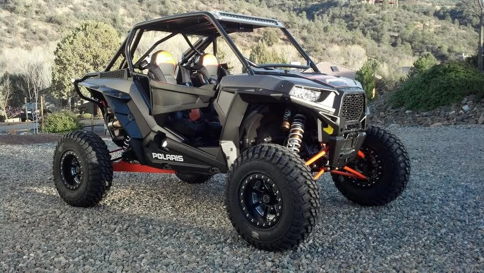 Custom modified Polaris RZR UTV with street legal upgrades parked in outdoor rocky terrain setting