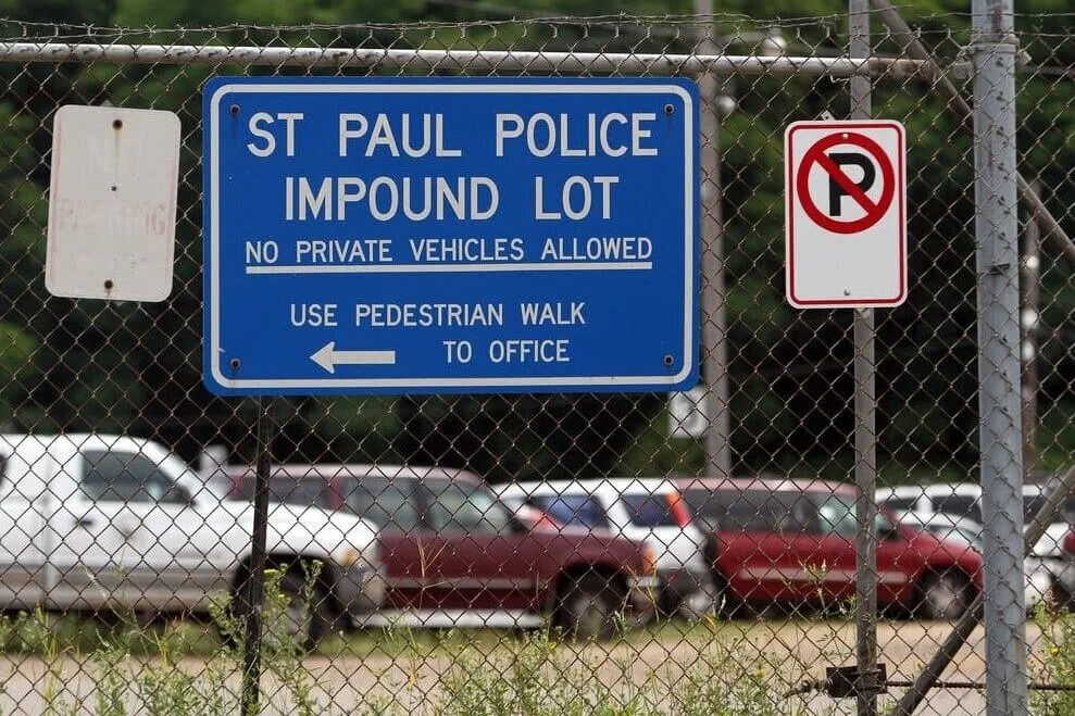 St. Paul Police impound lot with no private vehicles allowed sign and parked cars behind chain-link fence