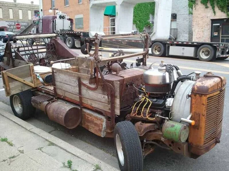 Rusty homemade kit car with custom engine and wooden bed on city street
