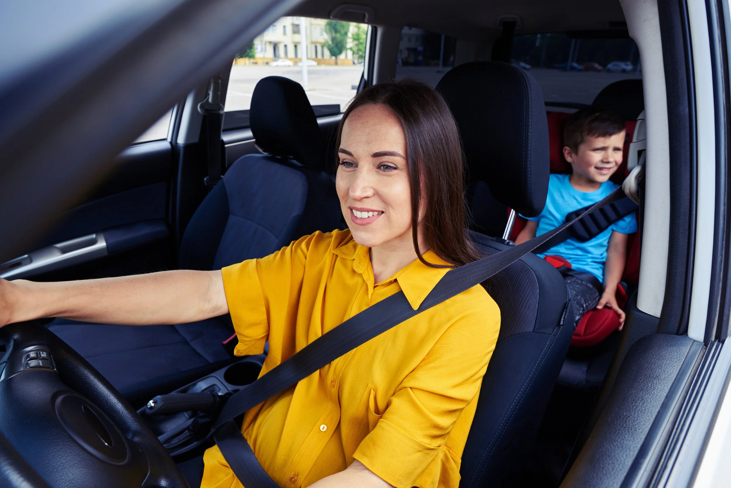 Happy mother in yellow shirt driving car with child passenger, simplifying family transportation solutions