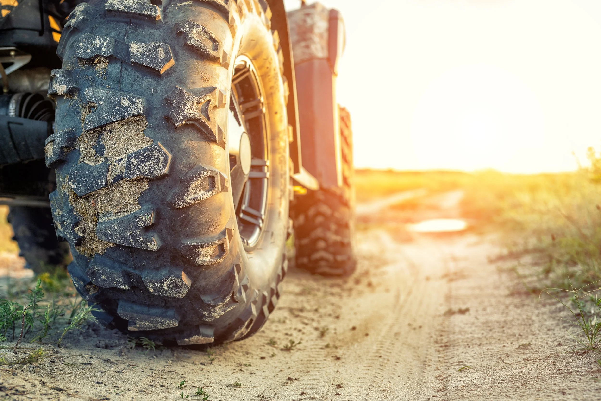 Off-road 4x4 truck tires caked with mud on dirt trail at sunrise, symbolizing adventure goals