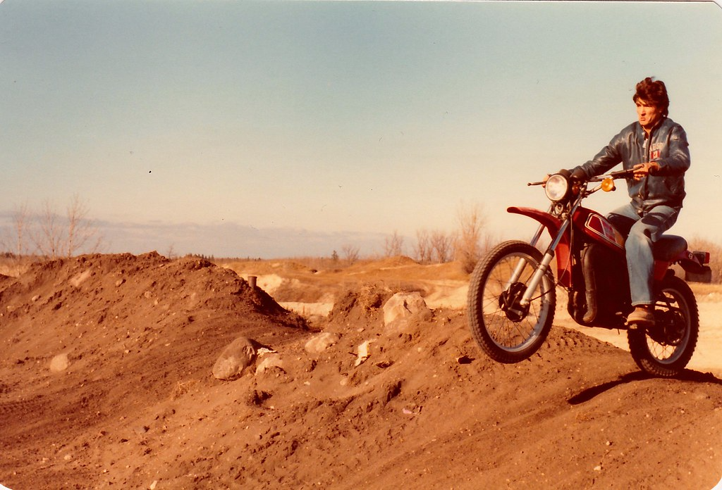 Vintage red 2-stroke dirt bike with rider on dusty desert terrain